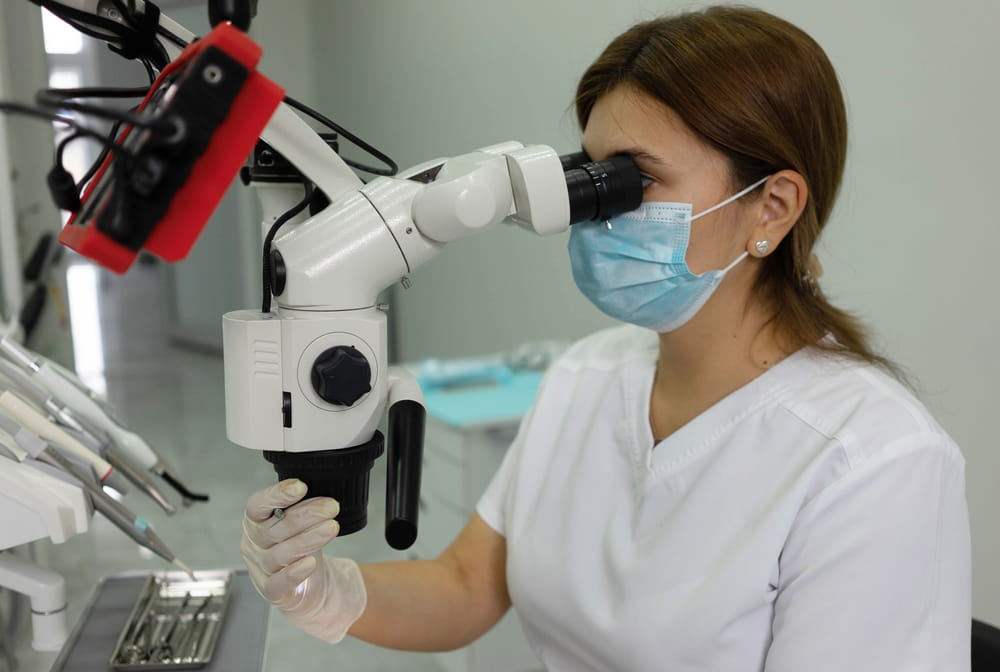 dentist looks through a dental microscope. The concept of using the latest equipment in medicine.