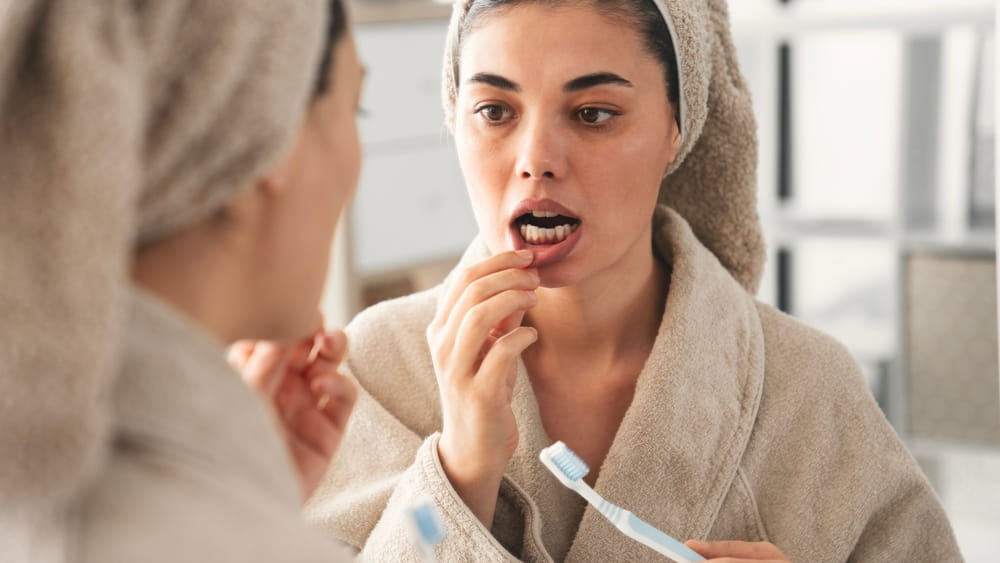 Reflection in a mirror young woman brushing teeth