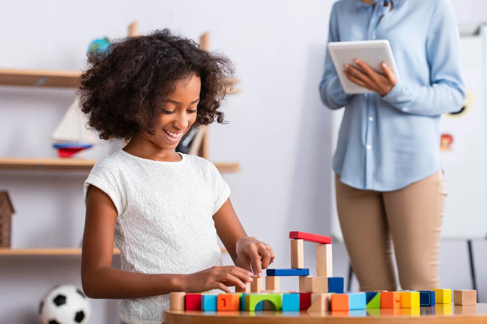 Happy girl playing with colorful wooden blocks at coffee