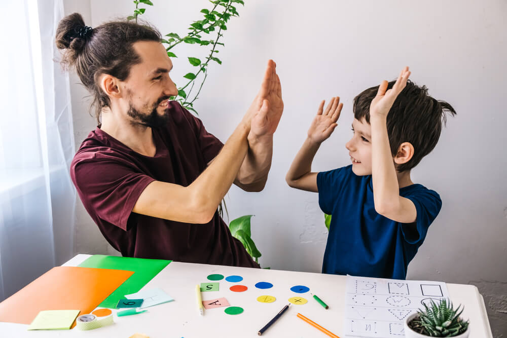 Happy autism boy during therapy with school tutor