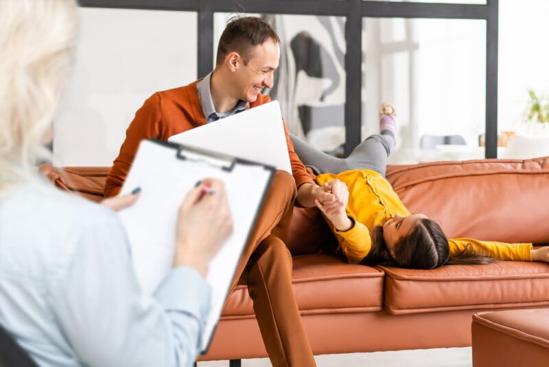 Hand of a professional family psychotherapist writing notes in front of a family with a child during a consultation