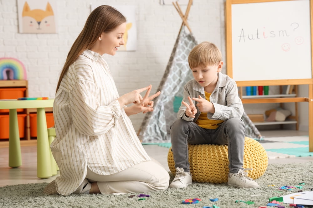 Female psychologist with little boy counting on fingers in office. World Autism Awareness Day