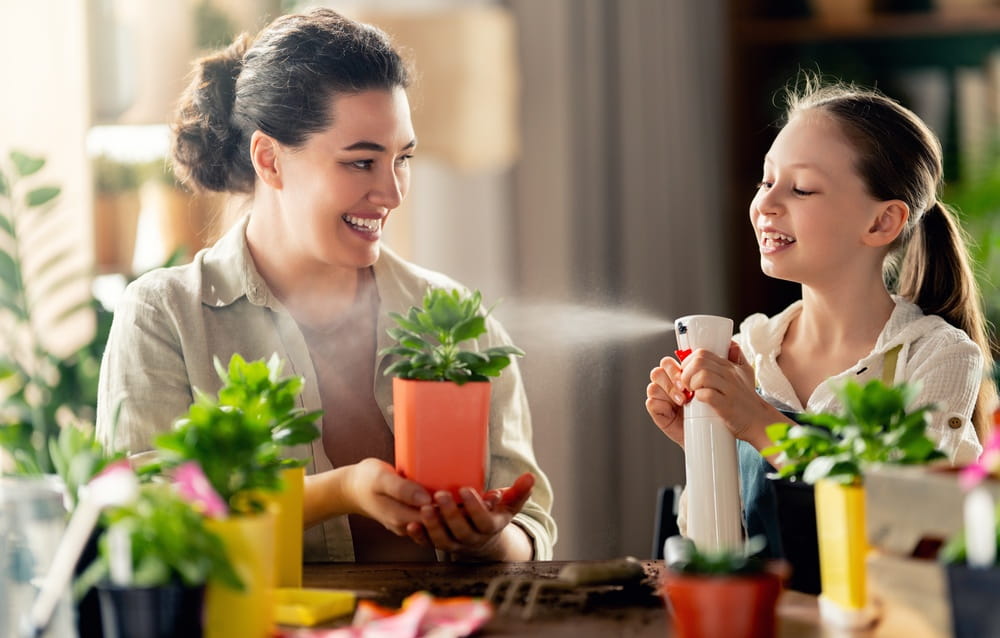 Heartwarming scene of a smiling mother and daughter enjoying quality time together while watering and caring for indoor plants