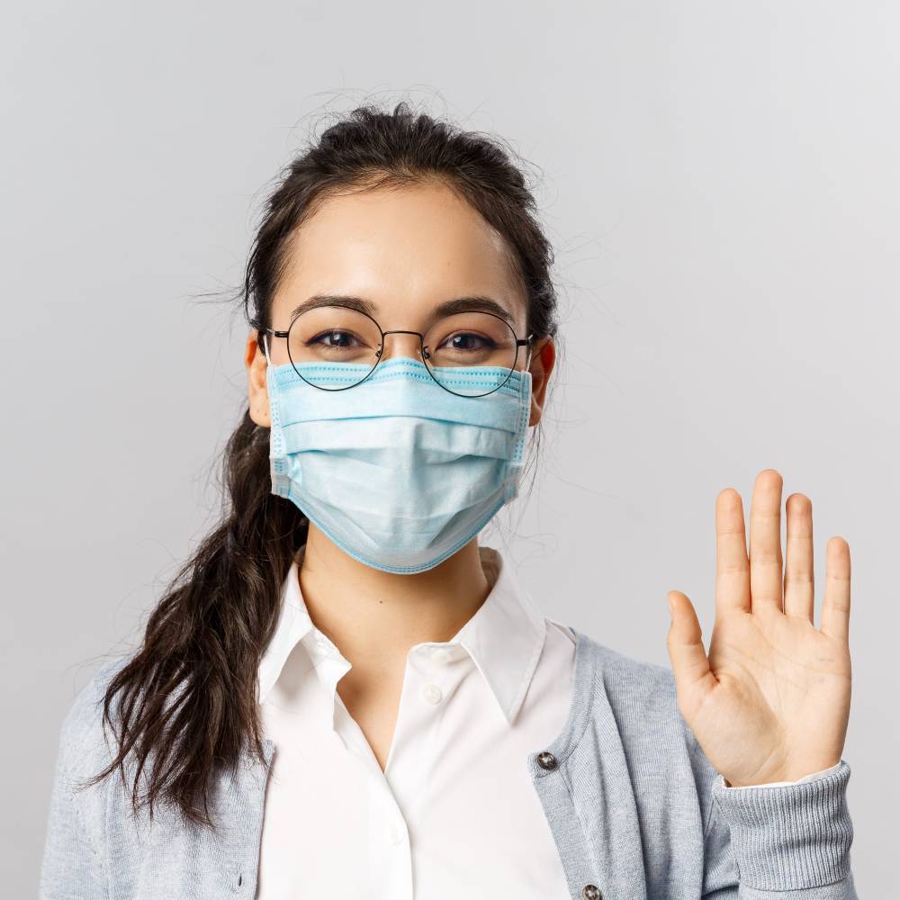 young girl in medical face mask saying hi