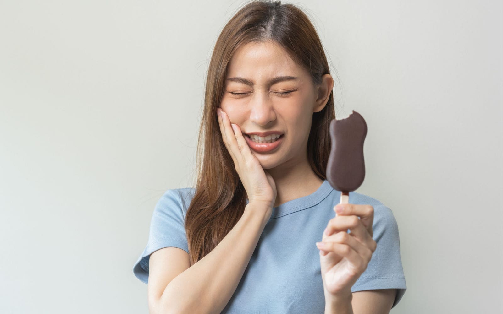 Woman Experiencing Tooth Sensitivity From Cold Ice Cream Bar