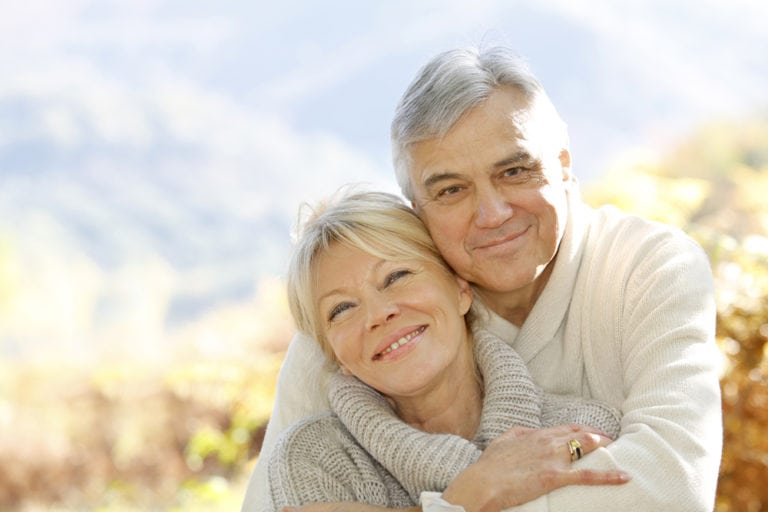 elderly man and woman holding each other smiling