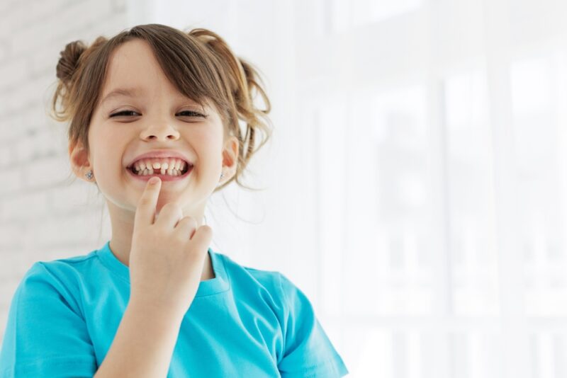 A child pointing at their missing tooth prompting for the need for Children's Dentistry