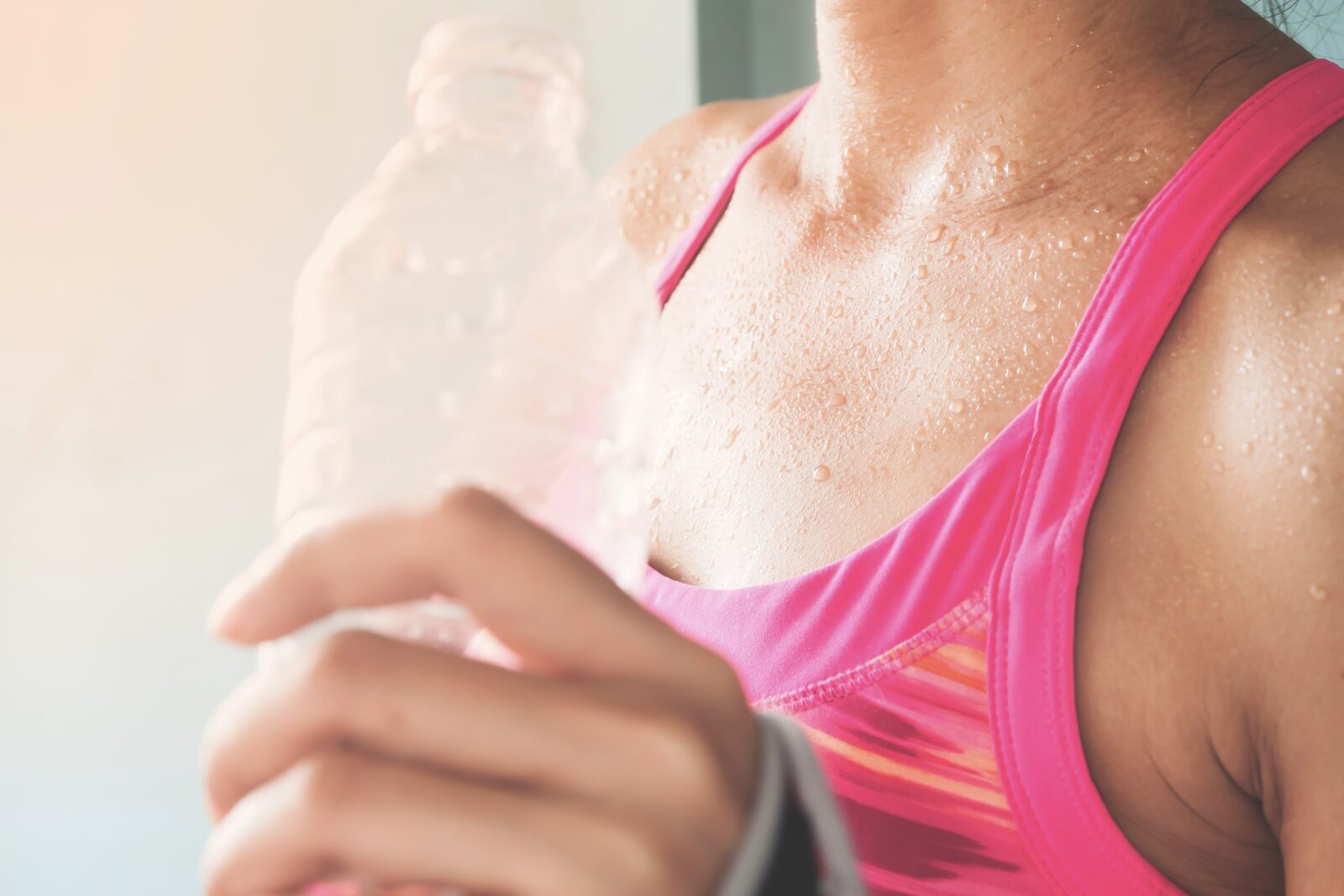 sweaty woman drinking water after a workout