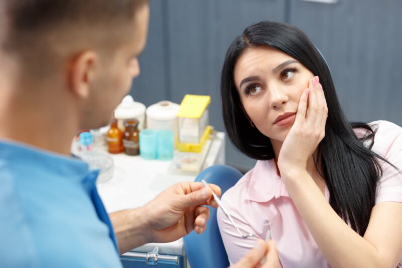 woman sitting in dental chair with tooth pain