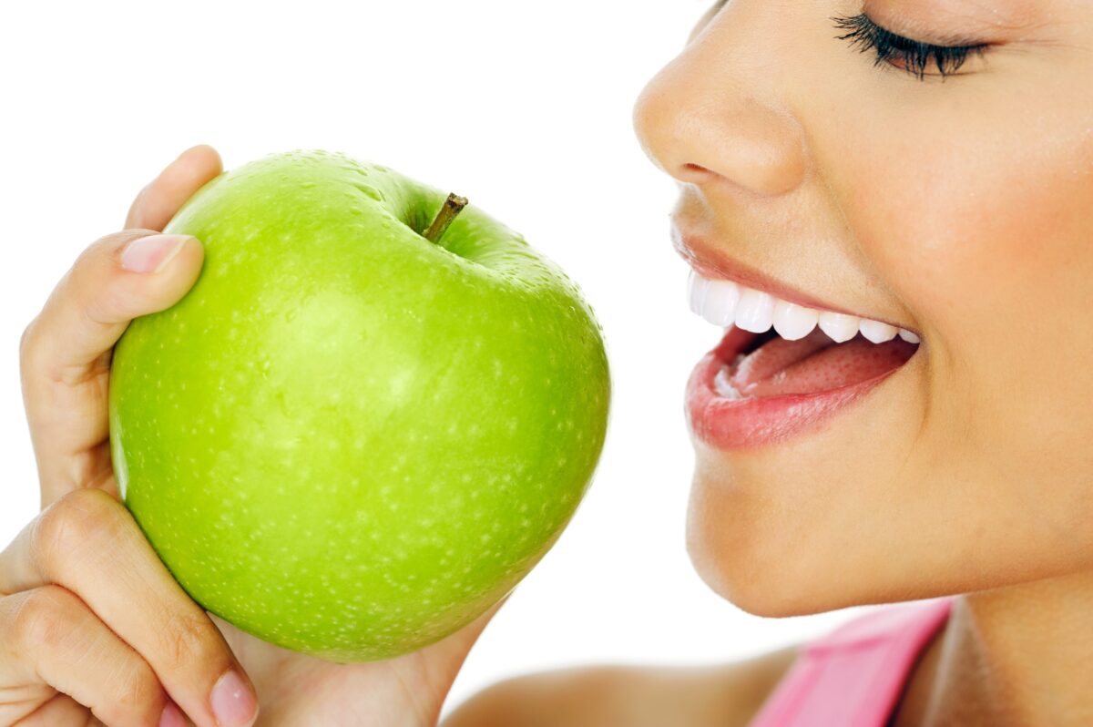 side view of woman biting into green apple