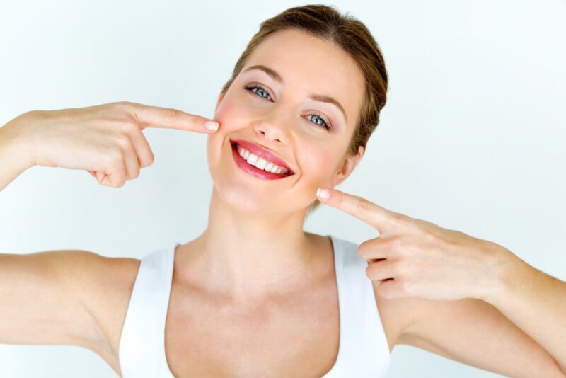Woman pointing to her white teeth