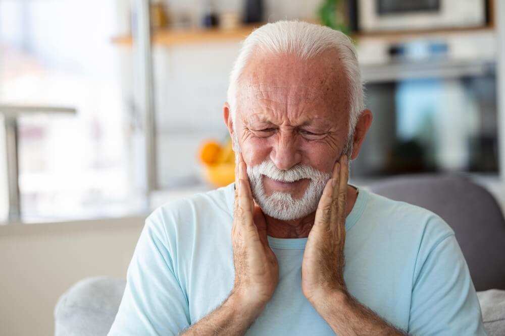 man holding his mouth in pain