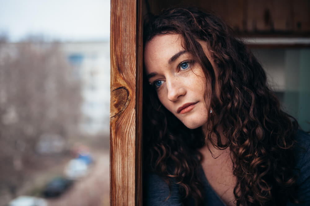 beautiful sad girl sitting near the window