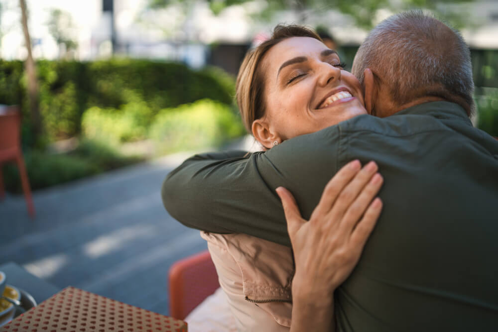 Woman hugging senior father outdoors in city