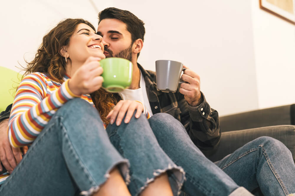 Young couple drinking coffee cup sitting on floor