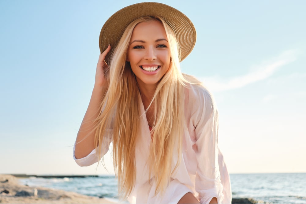 young smiling blond woman in white shirt and hat joyfully