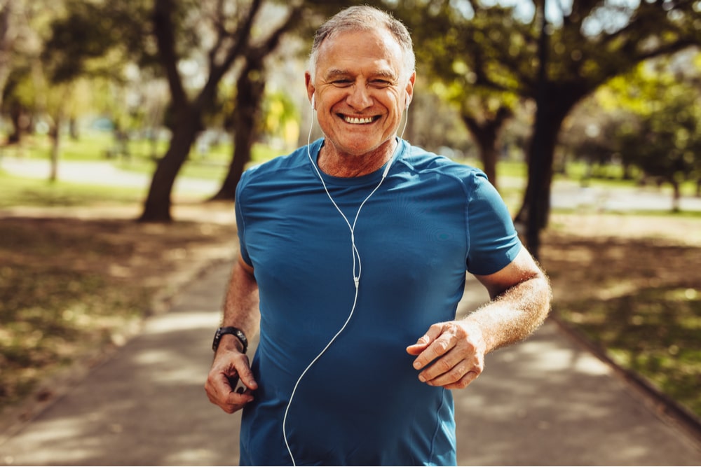 Close up of a smiling man running while listening to music