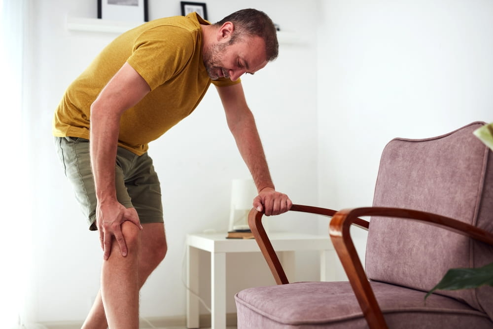 Man with painful knee and leg injury at home.