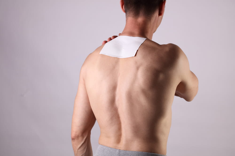 Medicated pain relief patch, plaster. man with back pain. Pain relief and health care concept isolated on white.