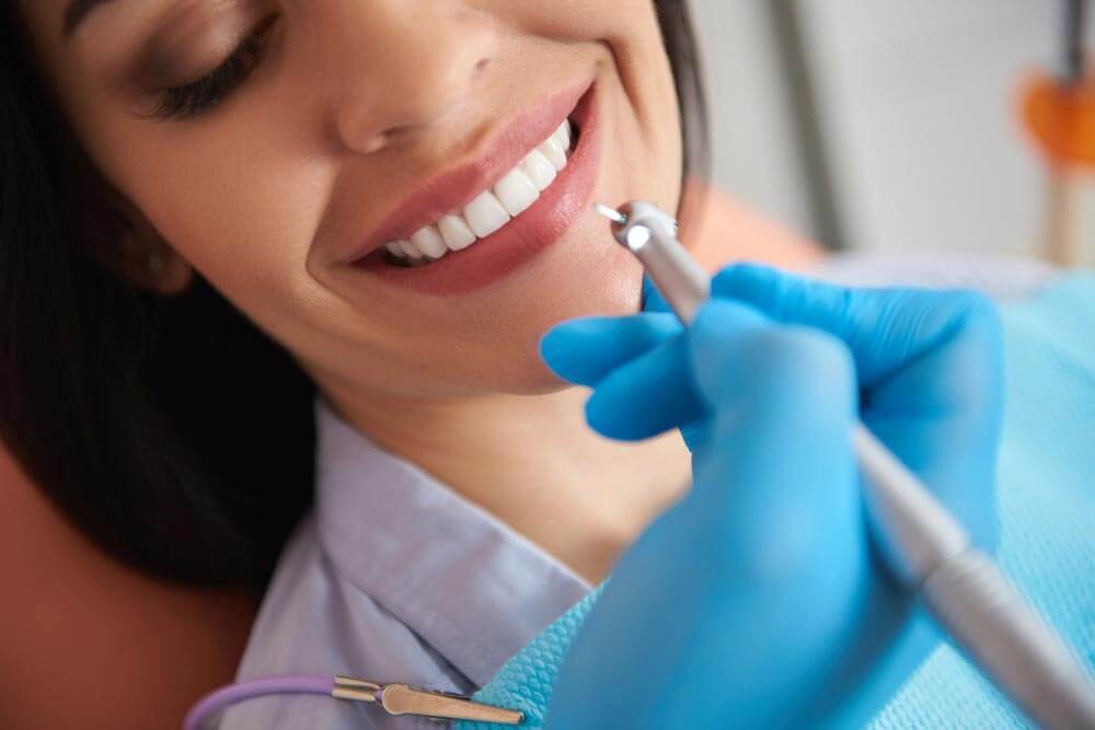 Smiling lady reciving professional teeth cleaning treatment