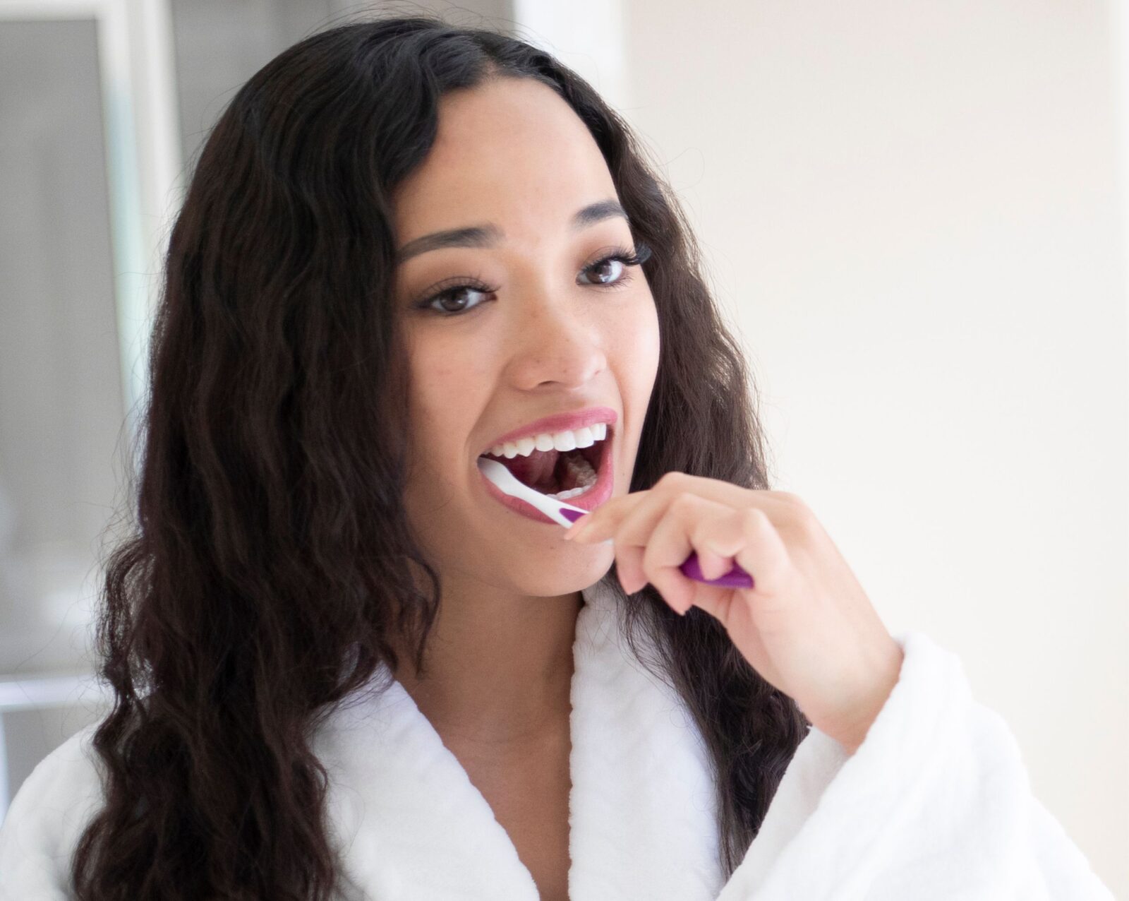 A dark haired young woman brushing her teeth