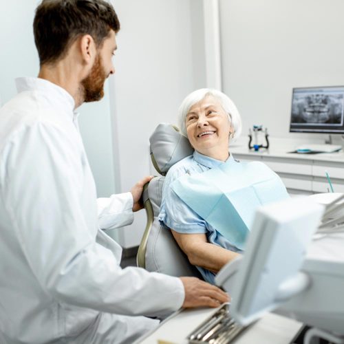 elder woman with healthy smile talking with dentist