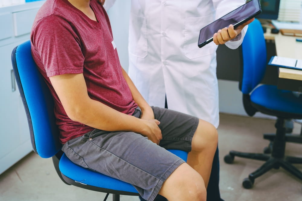 A man suffering from urinary tract infections visits a doctor at the examination table in a hospital.symptoms, discusses benign prostatic hyperplasia (BPH), and provides advice and treatment