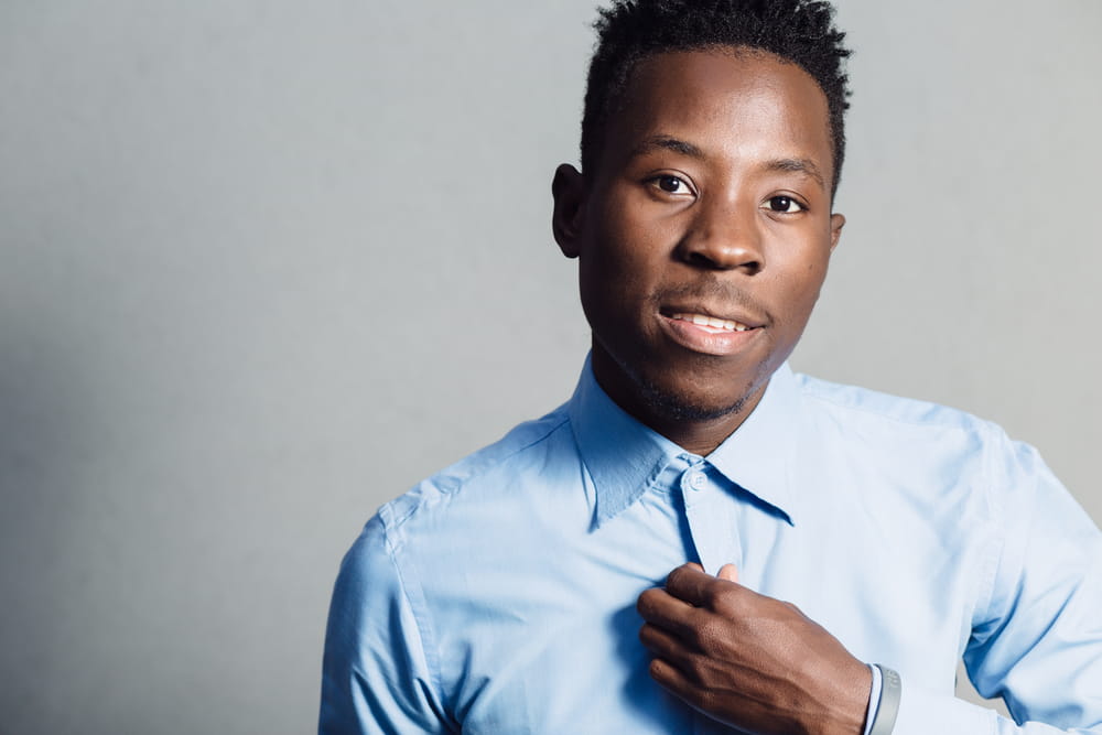 Classical portrait of african american man in blue shirt at grey wall background