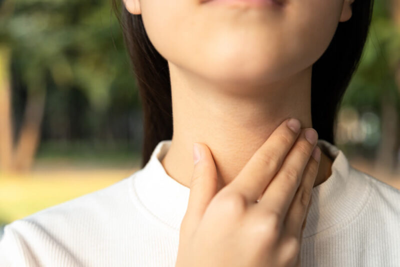 female people holding her inflamed throat