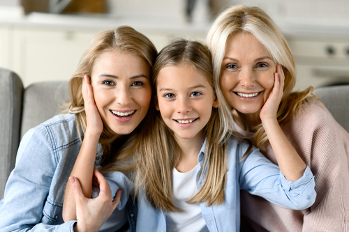 grandmother, daughter and granddaughter, are sitting on couch and smiling