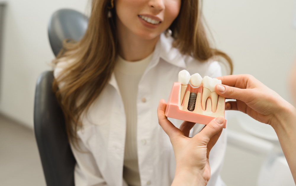 Dentist explaining Dental Implants to a patient using a dental model