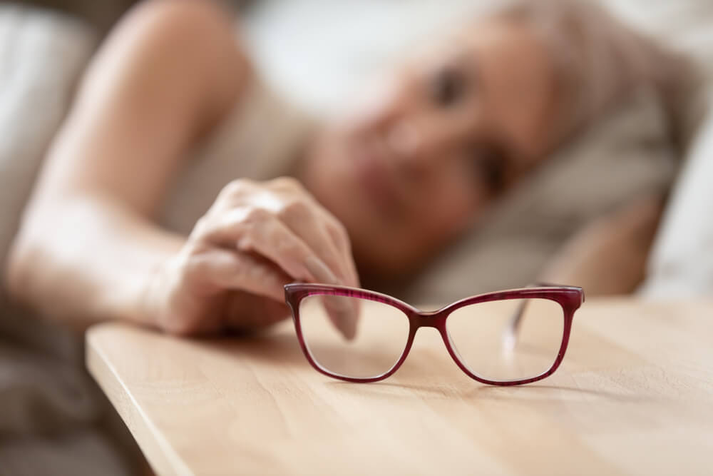 mature woman holding taking optical glasses