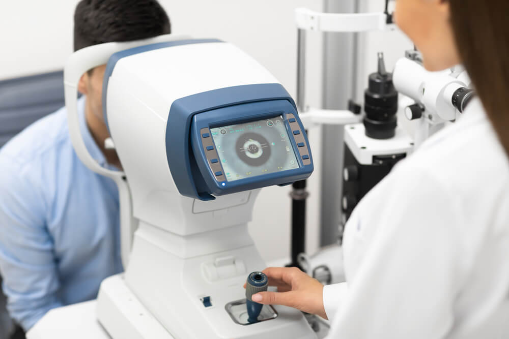 Female ophthalmologist checking eye vision of young male customer