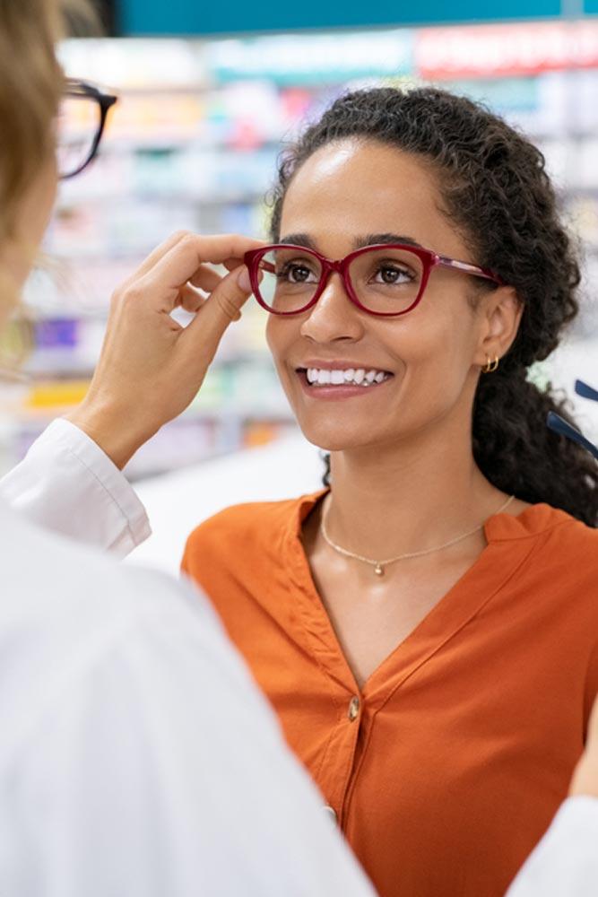 young woman in optic store choosing new glasses with optician