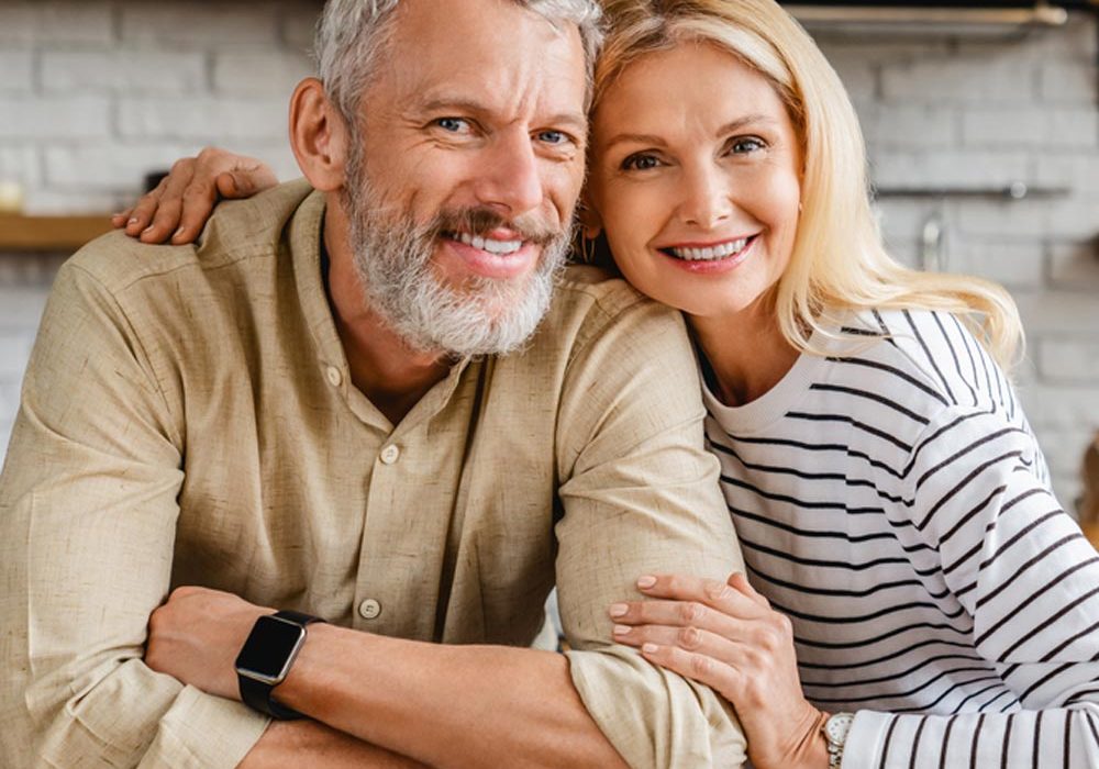 middle aged couple hugging while standing together