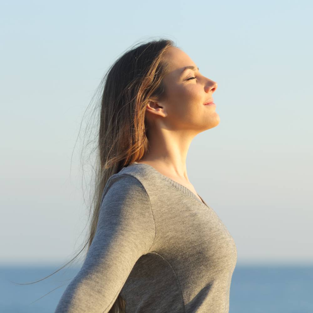 Side view portrait of a relaxed woman breathing fresh air on the beach