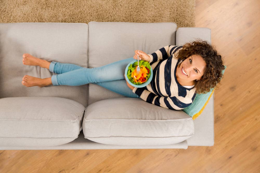 beautiful woman on the sofa eating a healthy salade