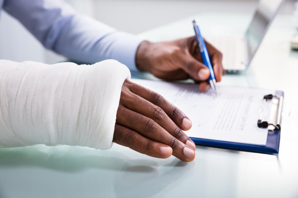 Injured Man With Bandage Hand Filling Insurance Claim
