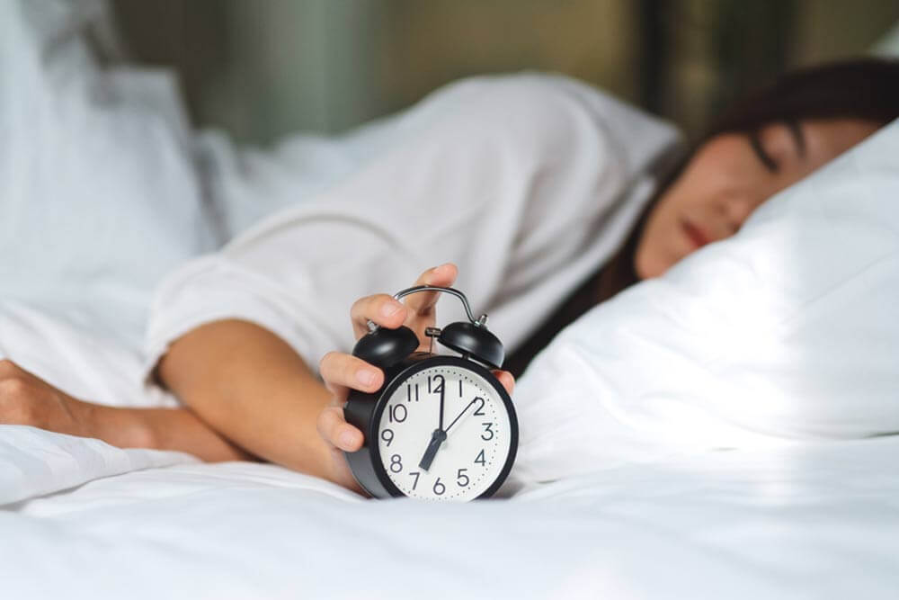 woman turning off an alarm clock