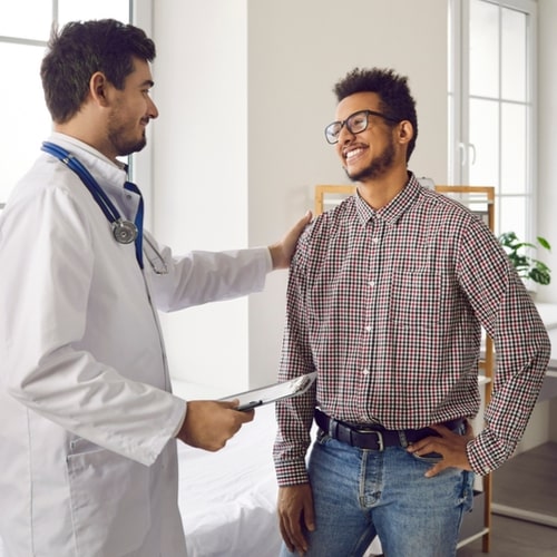 Happy, smiling young man talking to his doctor.