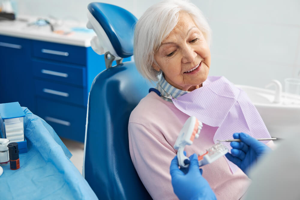 Senior citizen listening to orthodontist explanation of human teeth