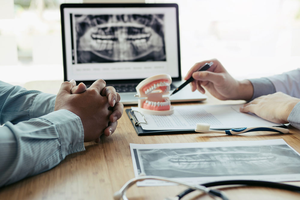 Dentists are discussing dental problems at report x-ray image on laptop