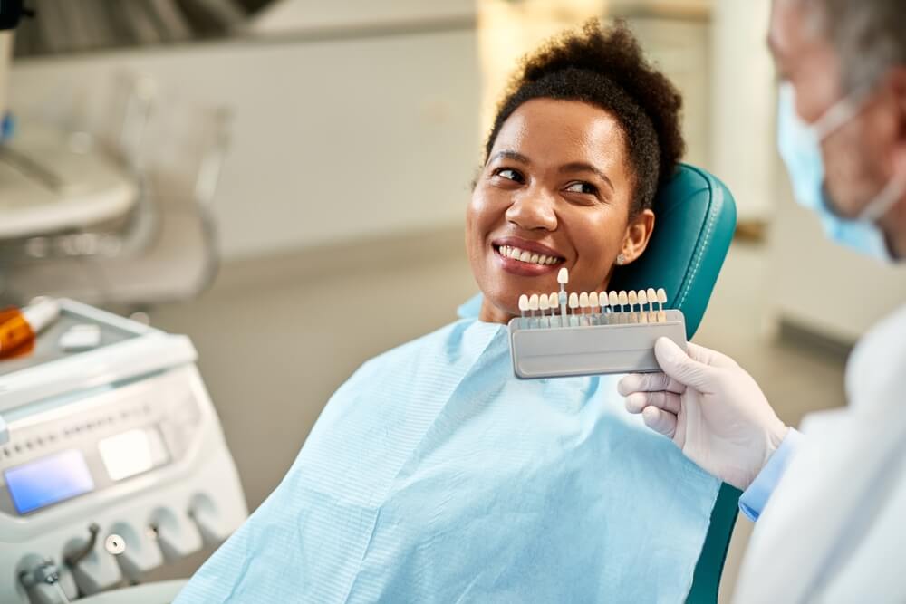 woman and her orthodontist choosing shade of implants during dental appointment