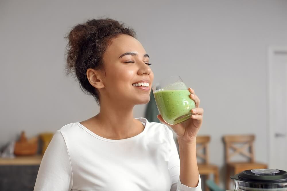 Young African-American woman drinking fresh smoothie