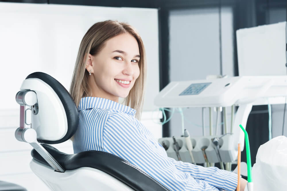 An attractive smiling girl blonde in a dental chair.