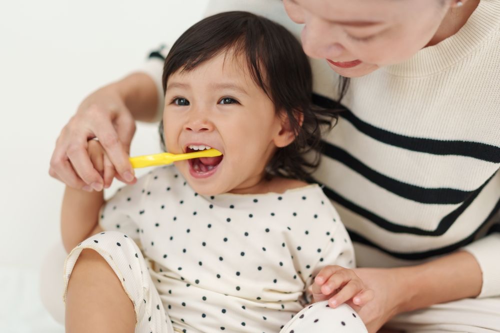 mother brushing her little daughters teeth