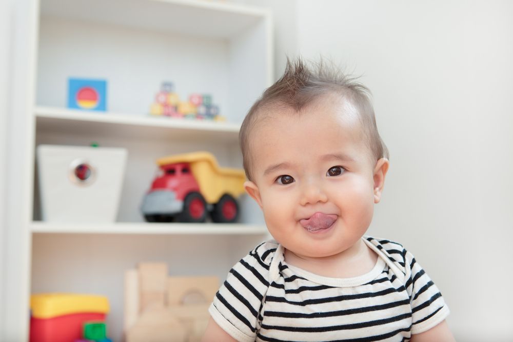 Head shot of a silly baby sticking his tongue out.
