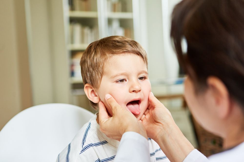 Female doctor examines throat and tongue in child
