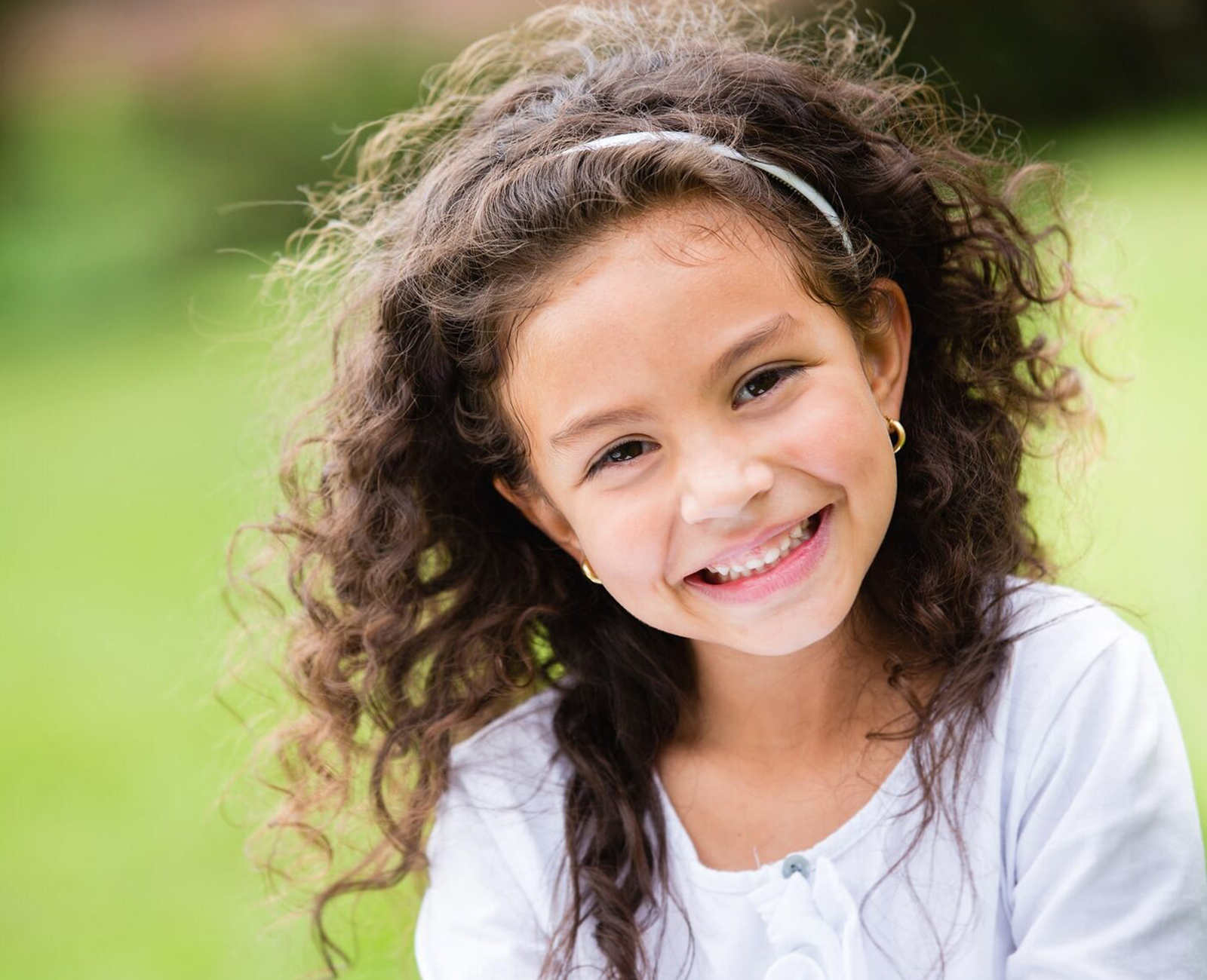 Sweet little girl outdoors with curly hair
