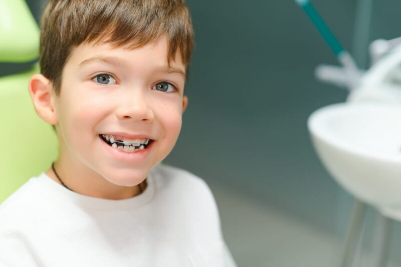 The boy inserts an orthodontic plate in his mouth.